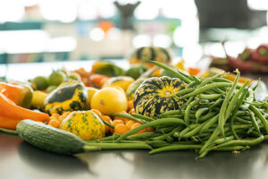 An assortment of farmer's market tomatoes, squash, and green beens arranged on a black kitchen counter top.