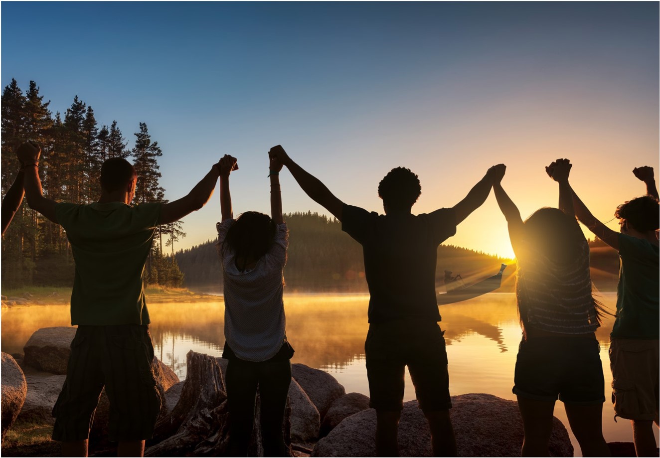 Des enfants se tenant la main sur la tête en regardant un canoë au coucher du soleil.